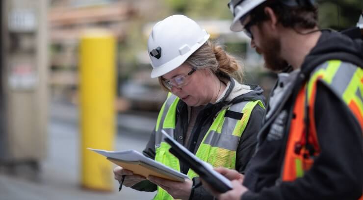 Two coworkers wearing hard hats and safety vests