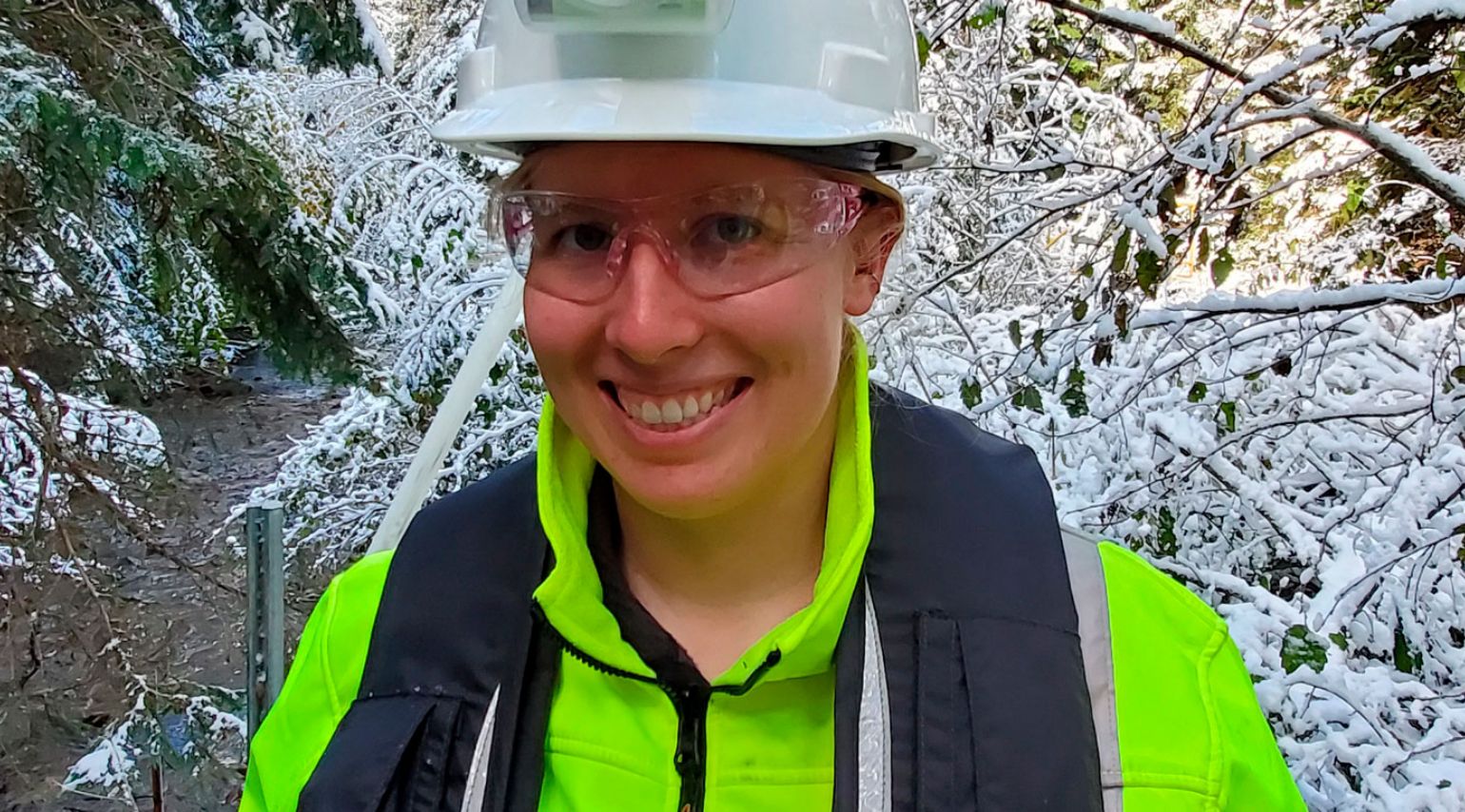 A woman with a hard hat on smiling.
