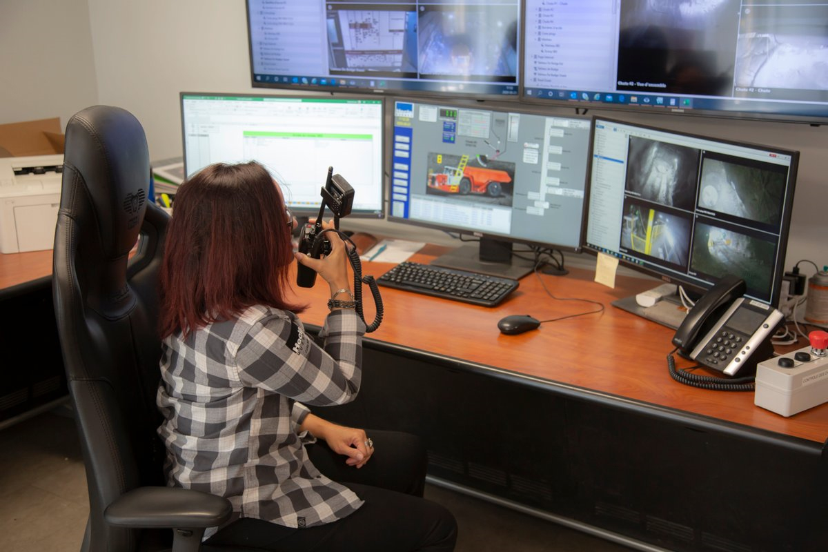 A woman using a walkie talkie by computers.