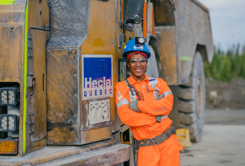 A woman smiling standing by a mining truck.
